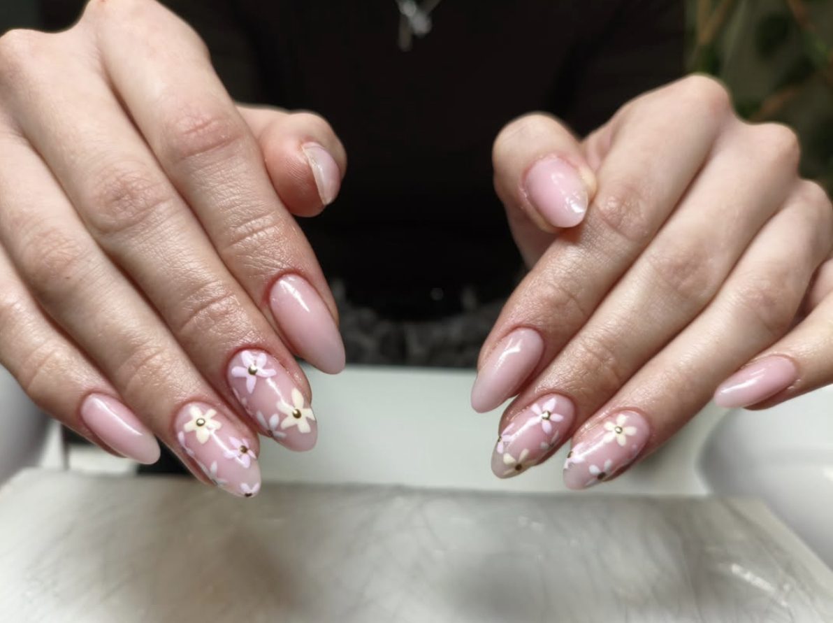 Soft pink almond manicure with daisy flower nail art and gold centers